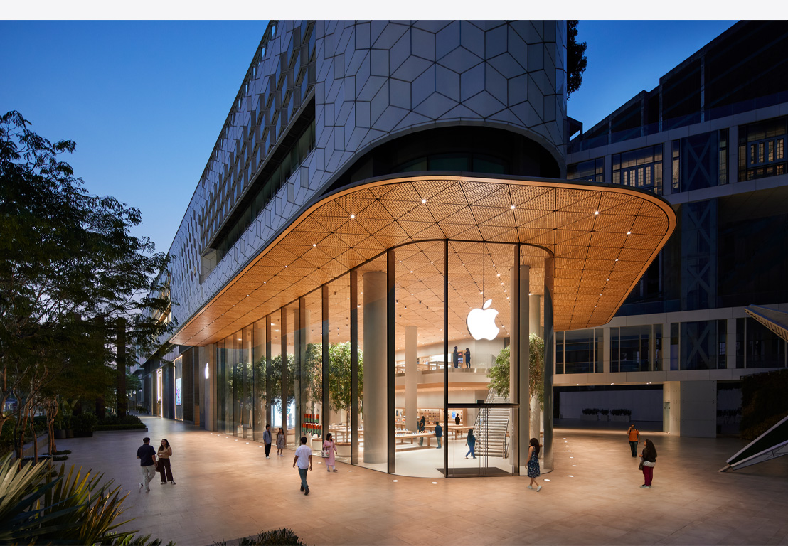 밤에 보는 Apple Store. 유리 통창 안으로 천장에 켜져 있는 조명들이 보이고, 정문 위쪽 중앙에 Apple 로고가 보입니다.