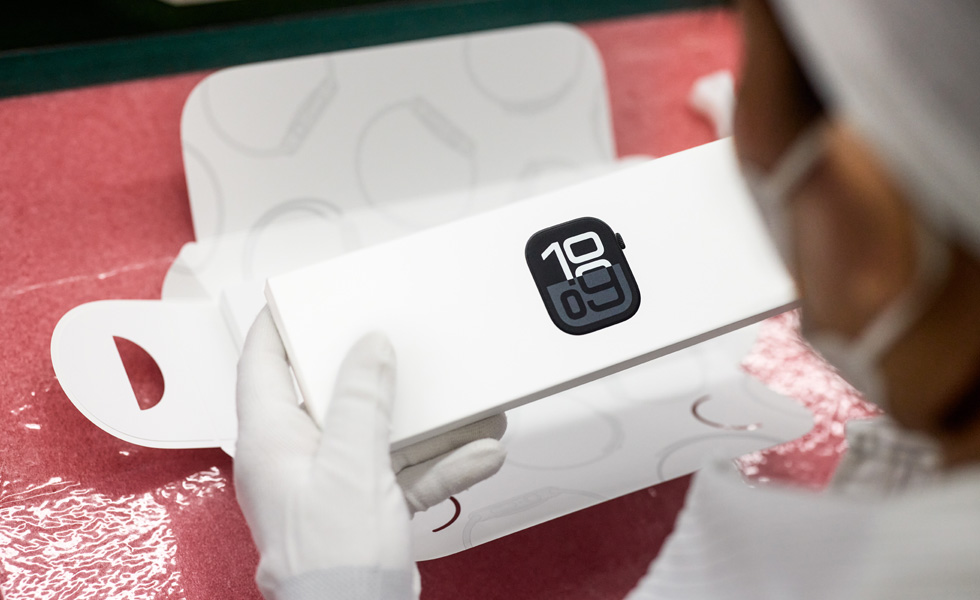 Bird’s-eye view of a masked employee packing up an Apple Watch